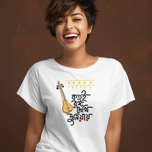 May include: White t-shirt featuring a stylized illustration of a violin and text in a foreign language. The violin is yellow and brown, with black details. The text is in black and red. The shirt is worn by a person.