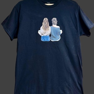 May include: Black t-shirt with a graphic of two women with their backs to the viewer, holding coffee cups. The women are wearing jeans and casual tops.