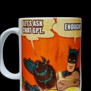 May include: White ceramic mug featuring a comic book style image of Batman and Robin. The mug has the text "LET'S ASK CHAT GPT..." and "ENOUGH!" in speech bubbles. The background is orange.