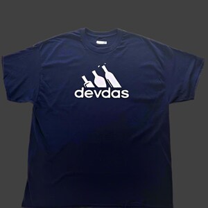 May include: Navy blue t-shirt with a white graphic. The graphic features three stylized wine bottles and the word "devdas" in a sans-serif font, resembling a well-known brand logo. The shirt is made of a soft material.