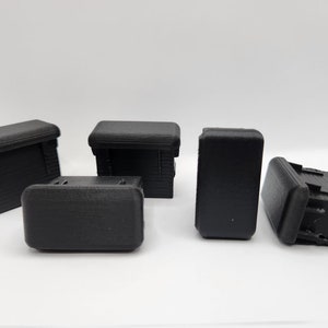 May include: Five black plastic rectangular boxes with rounded edges. The boxes are all the same size and shape.