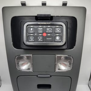 May include: A gray overhead console with a black AUXBEAM control panel featuring buttons for AUX, Under Glow, Fog Lights, Lightbar, Bumper, Rear, Radio, and Passystem.