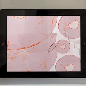May include: A digital tablet displaying an abstract art design with pink and orange colors. The design features overlapping circles with a textured, watercolor-like effect.
