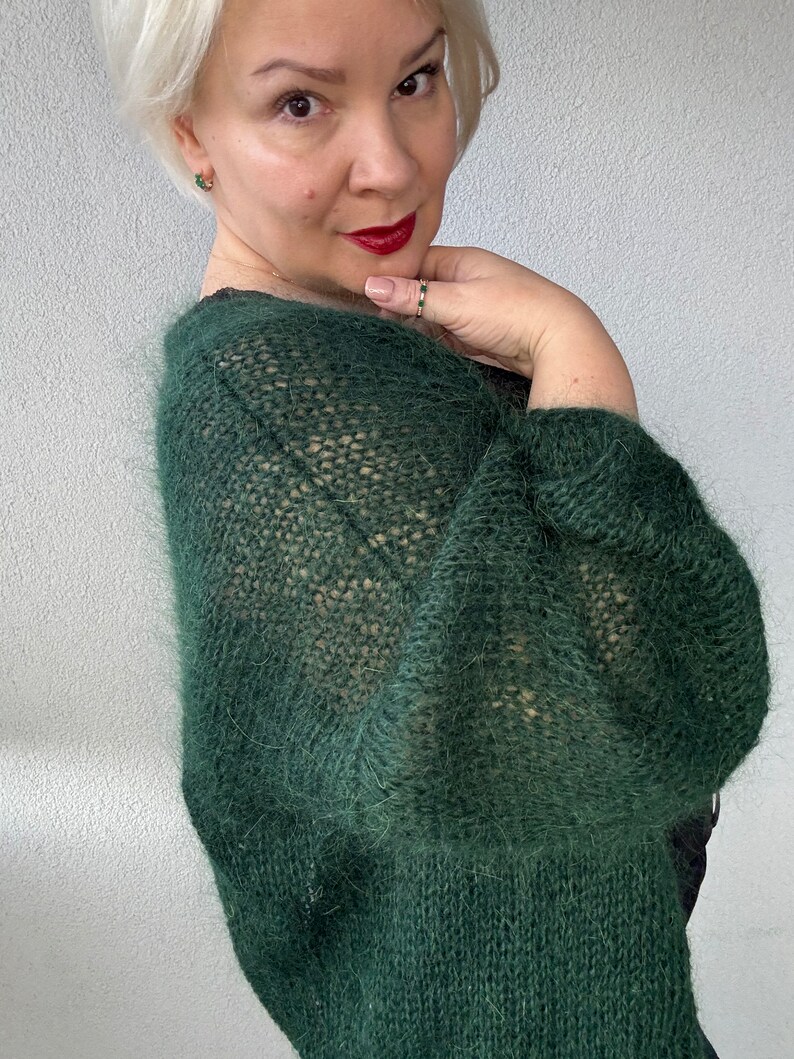 Puede incluir: Un c&aacute;rdigan de punto verde oscuro y peludo con un corte holgado y mangas largas. El c&aacute;rdigan est&aacute; hecho de un hilo suave y ligero y tiene un estilo relajado y casual.