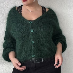 Puede incluir: Un c&aacute;rdigan verde oscuro y peludo con cuello en V y cierre de botones. El c&aacute;rdigan est&aacute; hecho de un hilo suave y esponjoso y tiene un ajuste holgado.