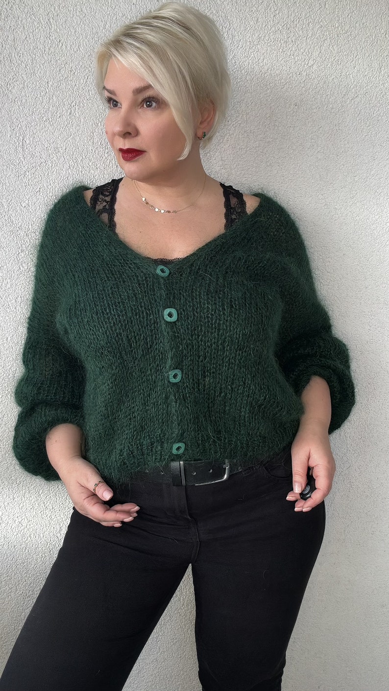 Puede incluir: Un c&aacute;rdigan verde oscuro y peludo con cuello en V y cierre de botones. El c&aacute;rdigan est&aacute; hecho de un hilo suave y esponjoso y tiene un ajuste holgado.
