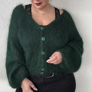 Puede incluir: Un c&aacute;rdigan verde oscuro y peludo con cuello en V y cierre de botones. El c&aacute;rdigan est&aacute; hecho de un hilo suave y esponjoso y tiene un ajuste holgado.