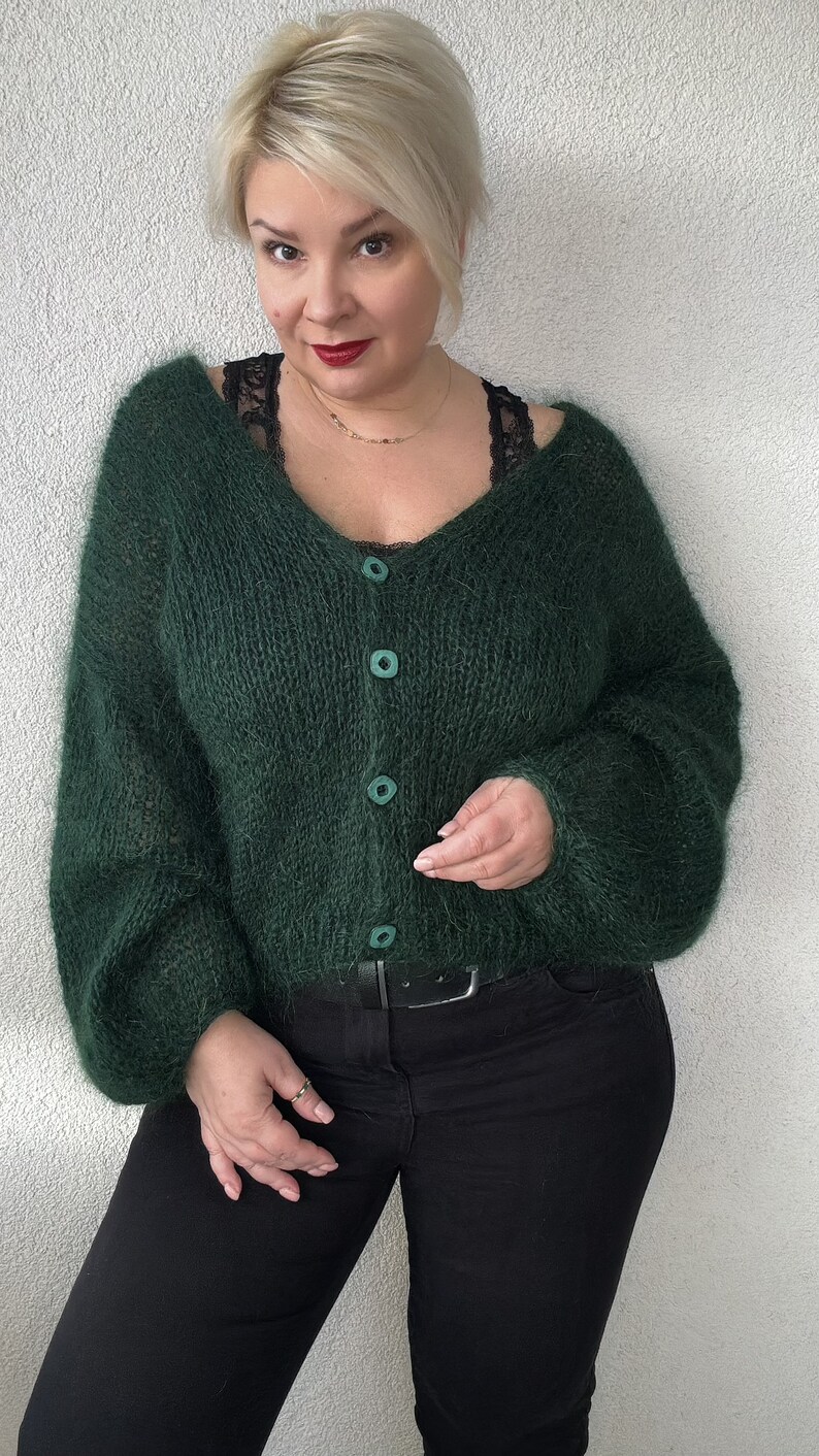 Puede incluir: Un c&aacute;rdigan verde oscuro y peludo con cuello en V y cierre de botones. El c&aacute;rdigan est&aacute; hecho de un hilo suave y esponjoso y tiene un ajuste holgado.