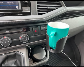 May include: A black car cup holder with a turquoise mug inside. The cup holder is attached to the dashboard of a car. The cup holder has a black cord attached to it.