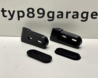 May include: Four black plastic pieces, two are long and rectangular with two holes, and two are oval shaped.