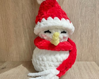 May include: A white crocheted snowman wearing a red Santa hat with a white pom-pom and a red scarf.