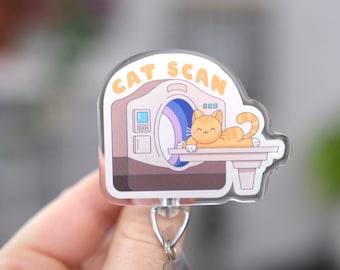 May include: A white and pink cat scan badge reel with a cartoon cat inside the scanner. The text "CAT SCAN" is printed in yellow on the badge reel.