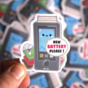 May include: A cartoon sticker of a medical device with a screen that says "The Morse Spot" and "MED-TELE". The screen shows a heart rate and a happy face with the text "NEW BATTERY PLEASE!" in a speech bubble.