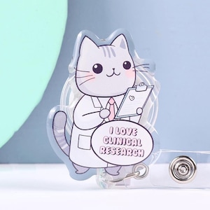 May include: A clear badge reel featuring a cartoon cat in a lab coat holding a clipboard. The cat has gray fur and a pink tie. Text on the badge reads "I LOVE CLINICAL RESEARCH". The reel has a clear plastic strap and a metal clip.