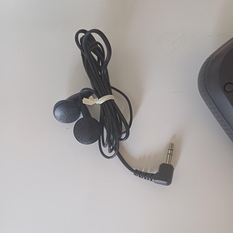 May include: Black wired earphones with a 3.5mm jack. The earphones have a black cord and a black rubber earpiece.