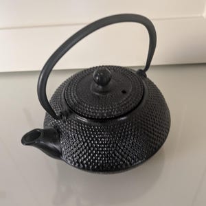 Tetera japonesa antigua de hierro fundido, pesada, con acabado negro y colador, en buen estado.