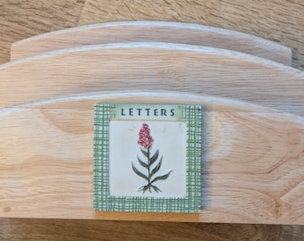 May include: A wooden letter holder with three tiers. The holder has a label that says "LETTERS" with a floral design.