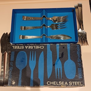 May include: A blue box with a silver knife and forks inside. The box is labeled "Chelsea Steel" and "Viners of Sheffield".
