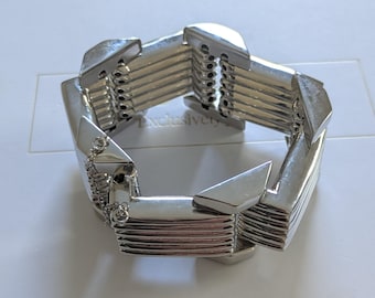 Pulseira vintage Alexis Bittar, estilo industrial modernista, robusta, em tom prateado, com corrente de segurança.