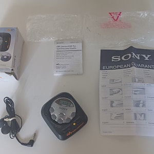 May include: A black Sony Walkman radio with a digital display and buttons. The radio is in its original packaging with a manual and warranty card. The radio is a small, portable device with a headphone jack.