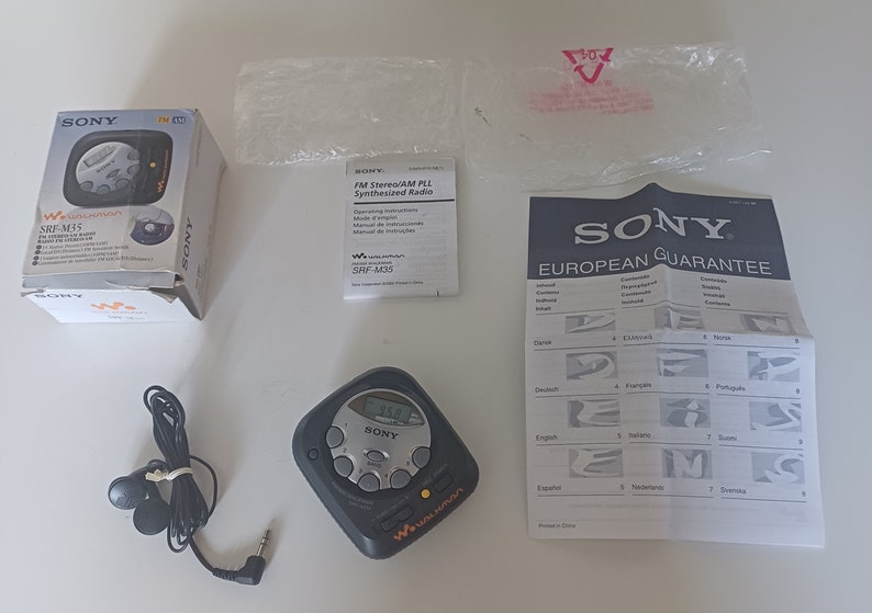 May include: A black Sony Walkman radio with a digital display and buttons. The radio is in its original packaging with a manual and warranty card. The radio is a small, portable device with a headphone jack.
