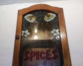 Vintage wall mounted spice rack with decorative glass fronted door, 8 standard jar capacity. 1980's