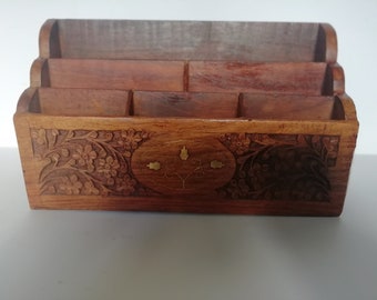 May include: A wooden desk organizer with three compartments and intricate floral carvings. The organizer has a brass inlay design in the center.