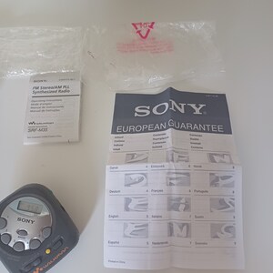 May include: A black and silver Sony Walkman SRF-M35 FM Stereo/AM PLL Synthesized Radio with a digital display showing 95.8. The radio has a European Guarantee card with instructions in multiple languages.