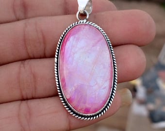 Op de afbeelding: Ovale hanger met een grote, iriserende roze edelsteen. De steen is gezet in een zilverkleurig metalen frame met een gedraaid touwontwerp rond de rand. De hanger heeft een kleine lus aan de bovenkant voor een ketting.