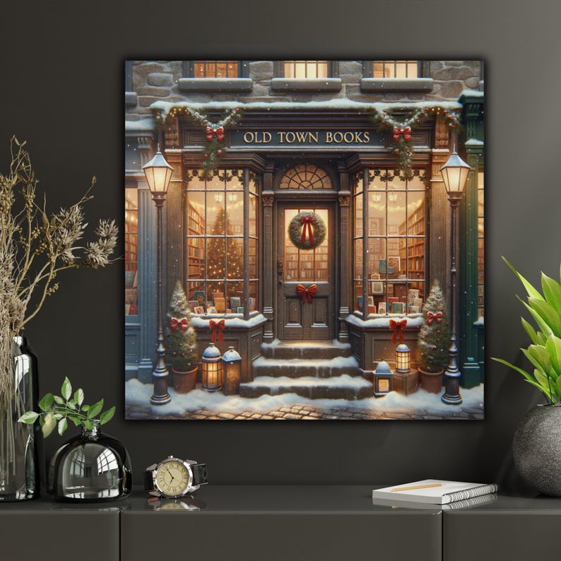 May include: A square wall art print depicting a storefront labeled OLD TOWN BOOKS, featuring a snow-covered entrance, a Christmas wreath on the door, glowing lanterns, decorated evergreen trees, and warm interior lighting visible through the windows.