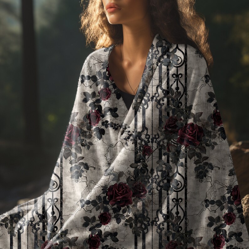 May include: A lightweight fabric wrap featuring a pattern of deep red roses and dark green leaves intertwined with black vertical ornate scrollwork lines against a textured light grey background, draped over the shoulders to cover the upper torso.