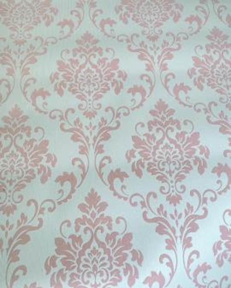 Puede incluir: Un papel tapiz azul claro con un patr&oacute;n repetido de dise&ntilde;os florales damasco de color rosa.