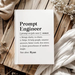 May include: A white book with the title "Prompt Engineer" in bold black letters. The book defines the term, including its pronunciation and three key attributes. The book is on a wooden surface with decorative elements.