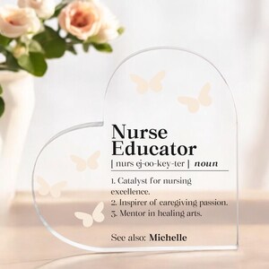 May include: A clear heart-shaped acrylic plaque with the words "Nurse Educator" and a definition of the term. The plaque is decorated with small butterfly cutouts.