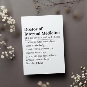 May include: A white card with black text defining the term "Doctor of Internal Medicine" with a phonetic pronunciation and a humorous definition. The card is on a gray background with white flowers.