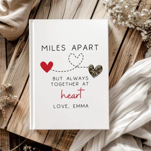 May include: White notebook with the text "Miles Apart But Always Together At Heart Love, Emma" and two red hearts connected by a dotted line.