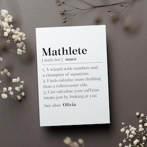 May include: A white card with the word "Mathlete" in bold black letters, defining it as a noun. The card lists characteristics of a math enthusiast, including a wizard with numbers and a champion of equations. The name "Olivia" is also listed.