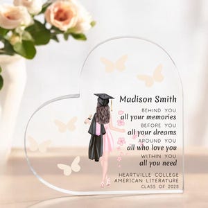 May include: A clear heart-shaped acrylic keepsake with a graduation cap and gown illustration, butterflies, and the text "Madison Smith" and "Heartville College American Literature Class of 2025".