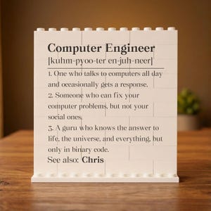 May include: A white brick-style sign with the words "Computer Engineer" and a phonetic pronunciation. The sign humorously defines a computer engineer, including the phrase "See also: Chris."