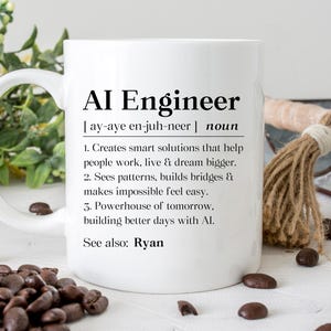 May include: White ceramic mug with the text "AI Engineer" in black, along with a definition. The mug includes a handle and is surrounded by coffee beans and decorative elements.