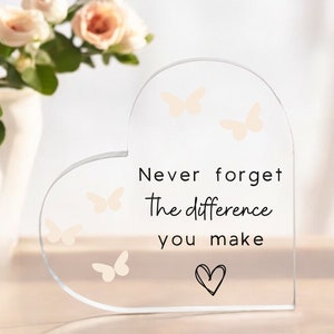 May include: A clear glass heart-shaped plaque with the text "Never forget the difference you make" and a small heart at the bottom. There are four small butterfly silhouettes on the plaque.