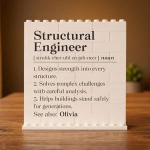 May include: A white rectangular sign constructed from interlocking plastic building bricks. The sign features black printed text defining the term Structural Engineer, including phonetic pronunciation, three numbered points, and the name Olivia.