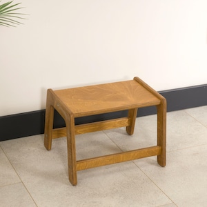 May include: A small, wooden step stool with a rectangular seat and four sturdy legs. The stool is made of light-colored wood with visible grain, and measures approximately 12 inches in height and 18 inches in length.