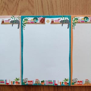 Peut inclure: Trois blocs-notes avec des pages blanches et des bordures décoratives. Chaque bloc-notes a une bordure de couleur différente : turquoise, rose et orange. Les bordures présentent des illustrations d'étagères avec des bols, des plantes et un chat gris endormi.