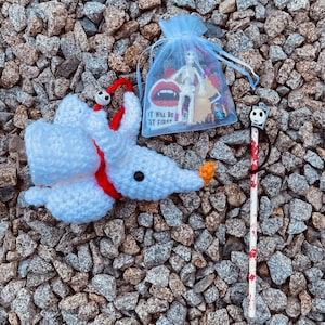 May include: A white crocheted Jack Skellington character with a red ribbon around its neck. A small blue bag with a skeleton toy and other Halloween themed items. A black and white Jack Skellington character on a red and white striped stick.