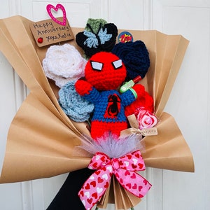 May include: A brown paper bouquet with a crocheted Spiderman figure, a pink bow with white hearts, and a card that says "Happy Anniversary! xoxo Katie".