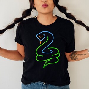 Op de afbeelding: Een zwart T-shirt met een neon groene, blauwe en oranje lijntekening van een slang op de voorkant.
