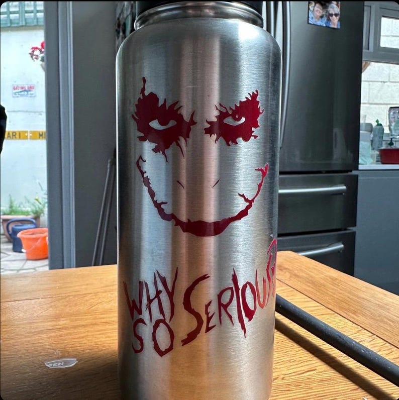 May include: A stainless steel water bottle with a red and white graphic of the Joker from the Batman movie. The graphic includes the Joker's face and the text "Why So Serious".