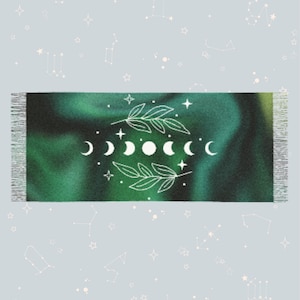 Może przedstawiać: Zielono-niebieski gobelin ombre z białym wzorem faz księżyca w kształcie półksiężyca i liści. Gobelin ma frędzle u góry i na dole.