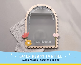 Op de afbeelding: Een boogvormige spiegel met een geschulpte houten lijst, voorzien van lasergegraveerde tekst met de woorden I am kind, I am smart, I am brave, I am loved, I am enough en I am Florence. De spiegel is versierd met twee platte, kleurrijke bloemen.